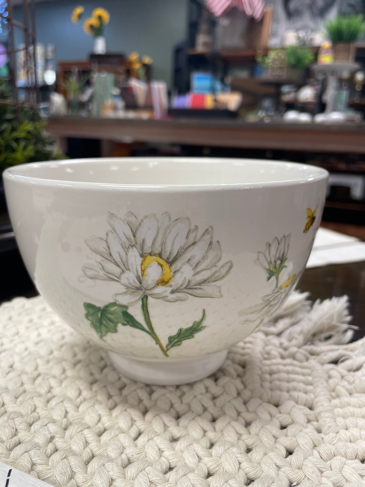 White ceramic bowl with daisies and bee design with macremae placemat