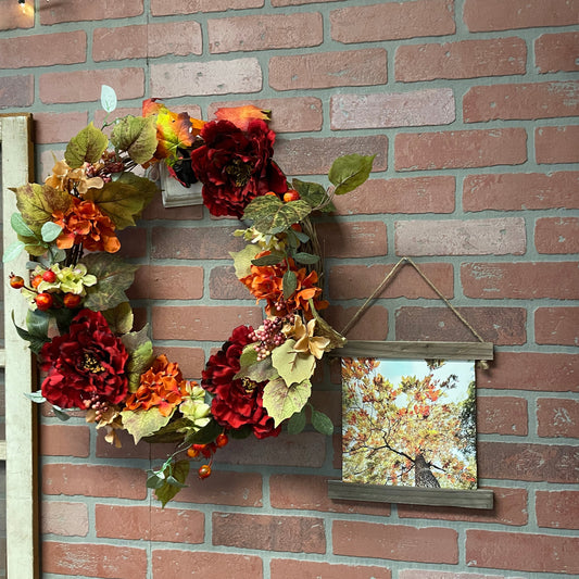 Decorative wreath with autumnal flowers on a brick wall