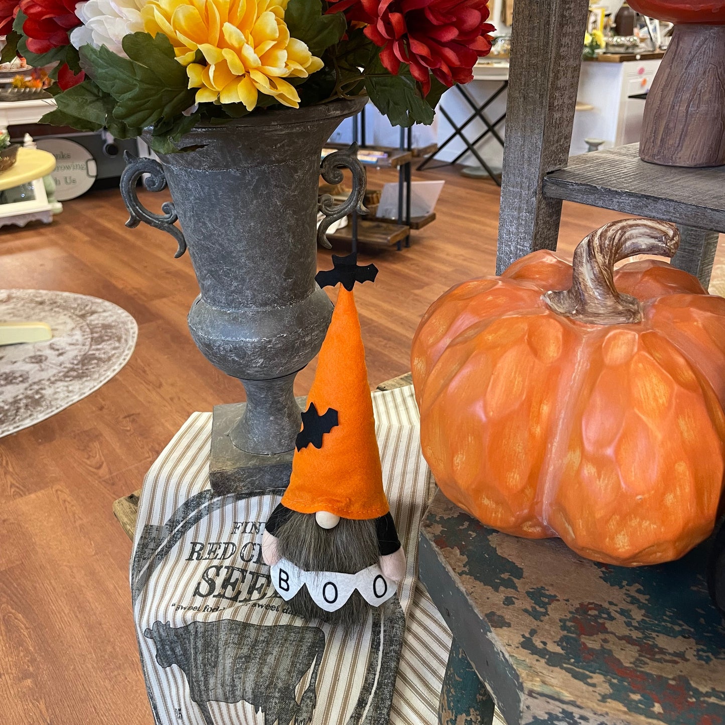 Decorative items including a pumpkin, scarecrow, and flowers on a table.