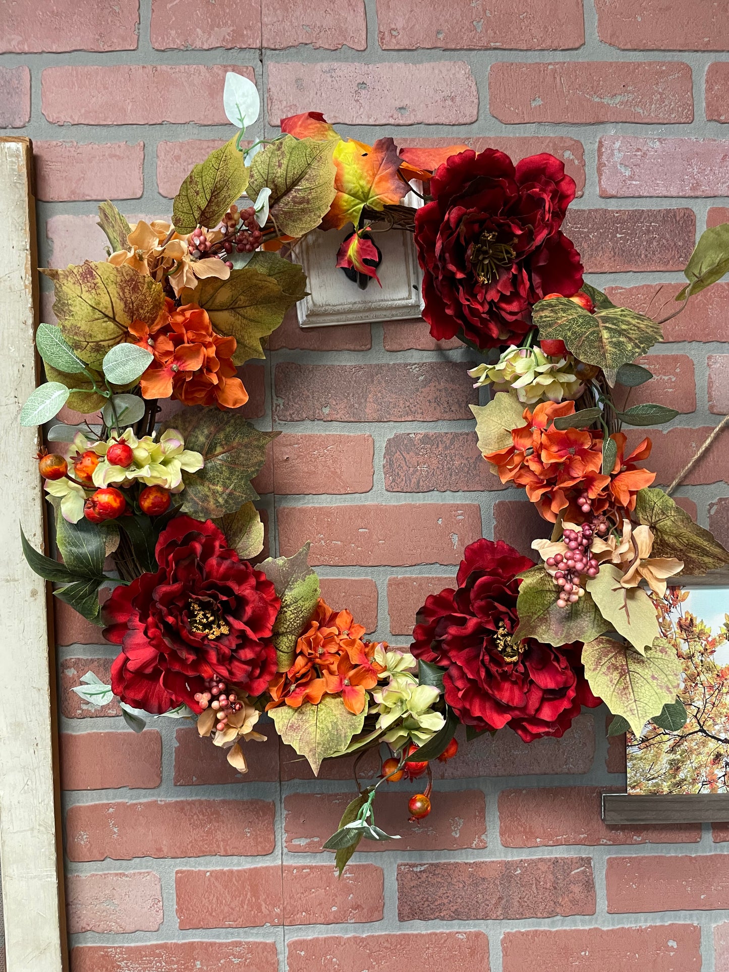 Decorative wreath with autumnal flowers on a brick wall background