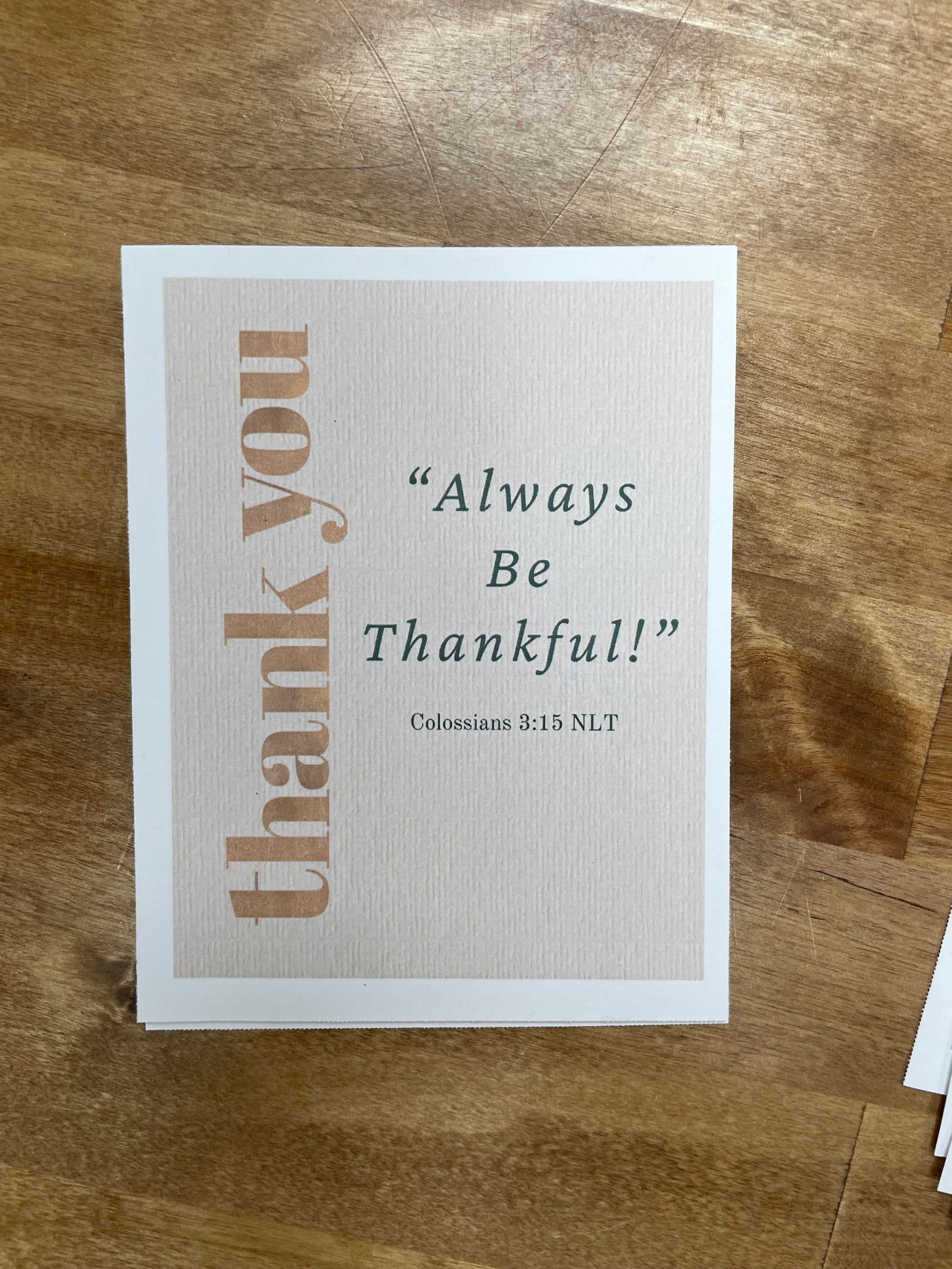 Card with 'Always Be Thankful!' text on a wooden surface