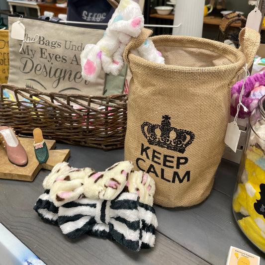 Burlap bag with 'Keep Calm' text on a table with various items including a basket and toys.