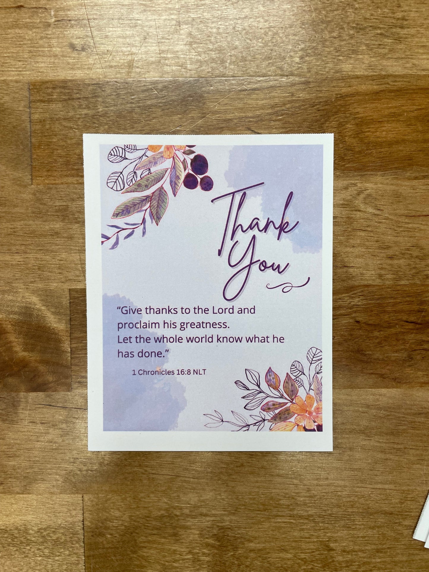 Greeting card with floral design and 'Thank you' text on a wooden surface