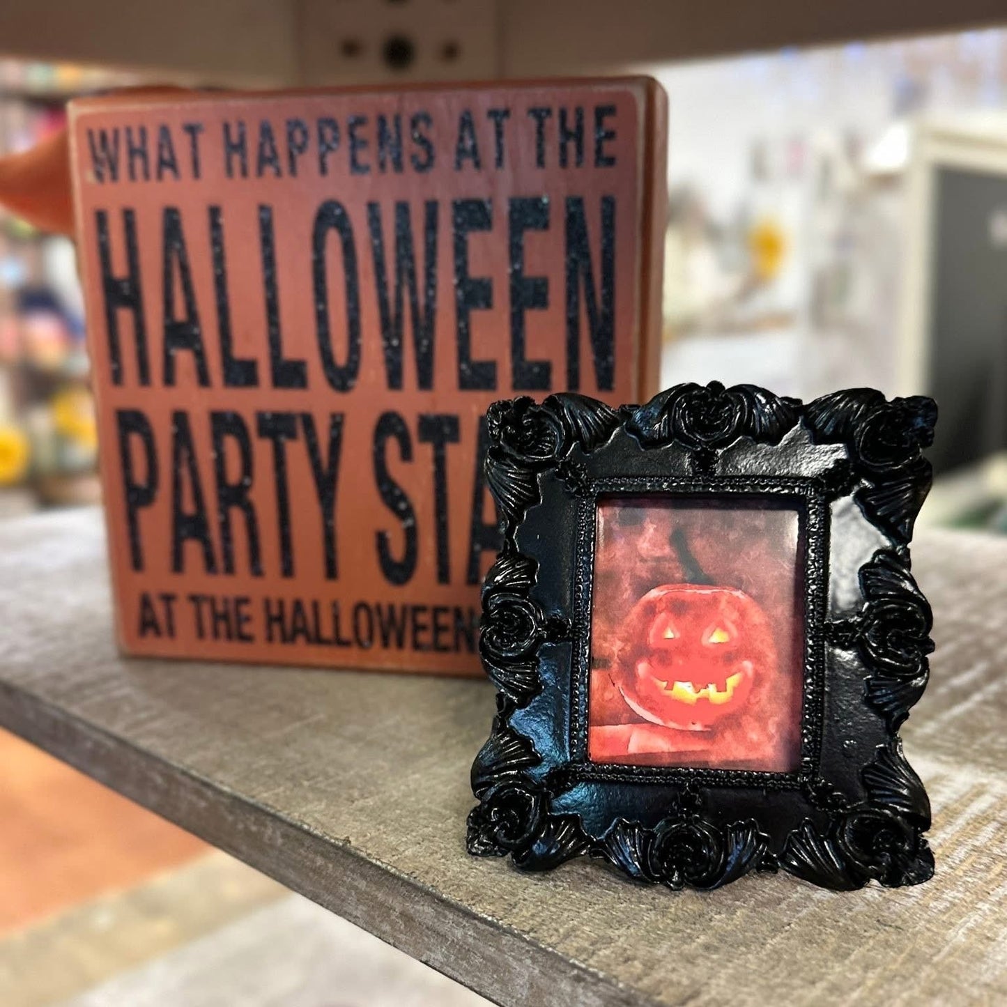 Decorative Halloween frame with a glowing jack-o'-lantern inside, placed on a shelf.