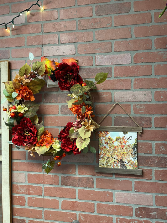 Decorative wreath with autumnal flowers on a brick wall